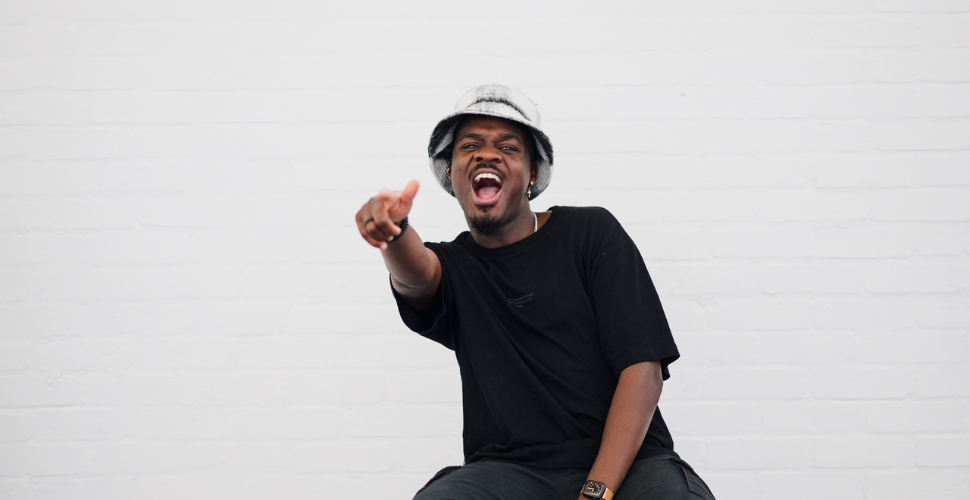 Dj Jozzy crouching in front of a white background